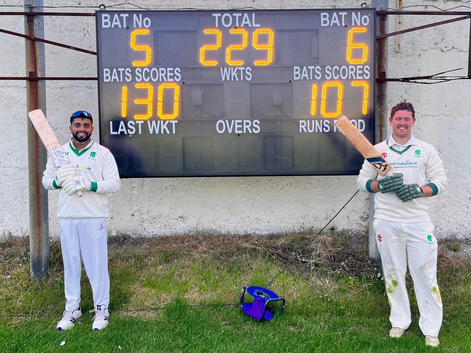 Image of t2 players alongside scoreboard after scoring hundreds